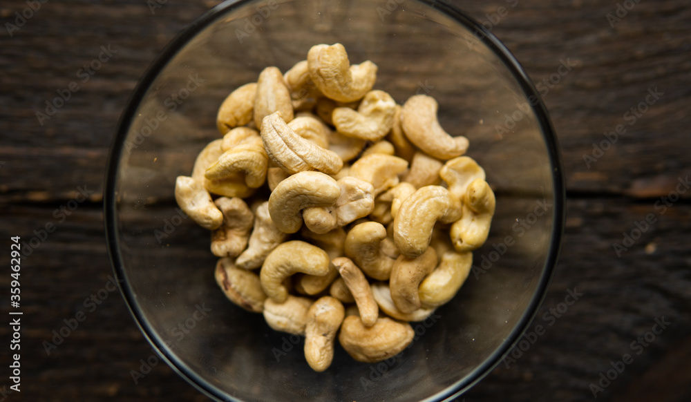 Cashew nuts in a small plate on a vintage wooden table as a background. Cashew nut is a healthy vegetarian protein nutritious food. Cashew nuts in a small plate on a vintage wooden table as a background. Cashew nut is a healthy vegetarian protein nutritious food.