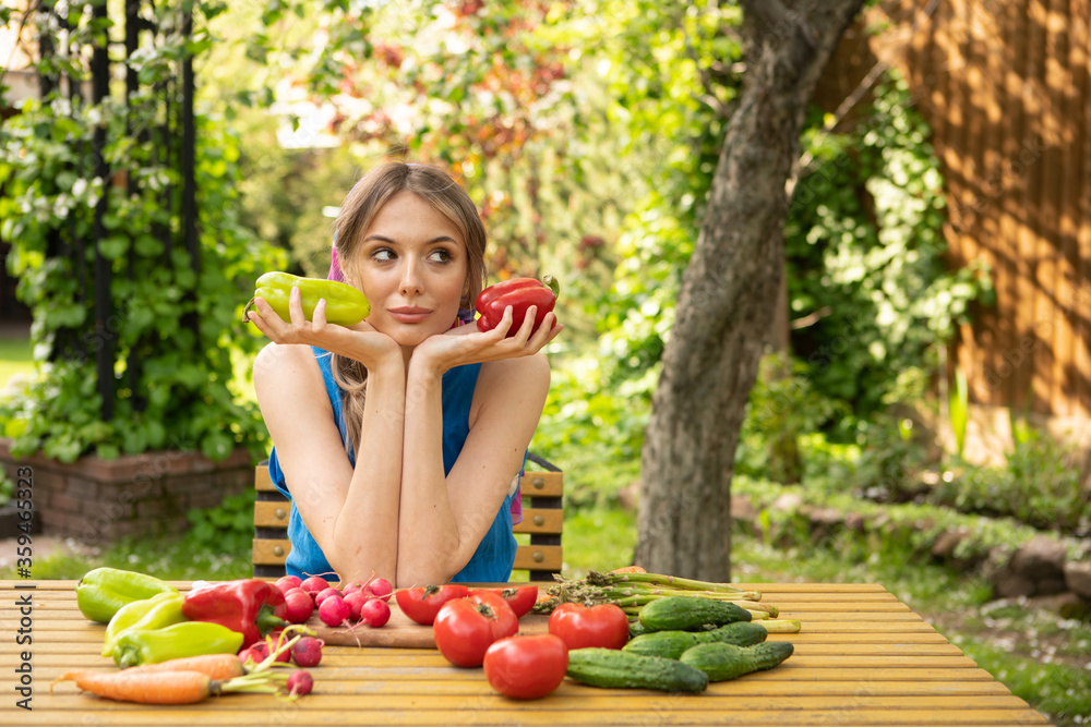 Young dreaming girl with organic vegetables and pepper in hands is sitting at table, photography for blog or advertising Young dreaming girl with organic vegetables and pepper in hands is sitting at table, photography for blog or advertising