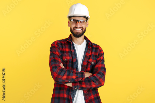 Attractive bearded engineer or constructor man in plai shirt standing over yellow background. Looking in camera. photo