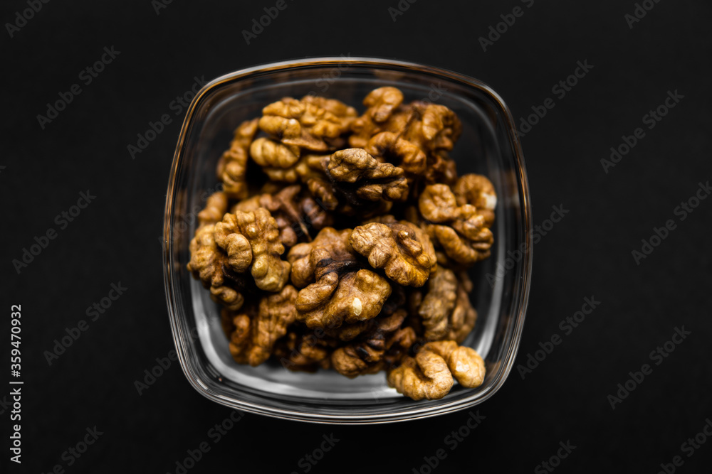 Walnut in a small plate on a black table. Walnuts is a healthy vegetarian protein nutritious food. Natural nuts snacks. Walnut in a small plate on a black table. Walnuts is a healthy vegetarian protein nutritious food. Natural nuts snacks.