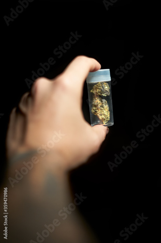 Hand of a young boy with tattoos holding a pot container