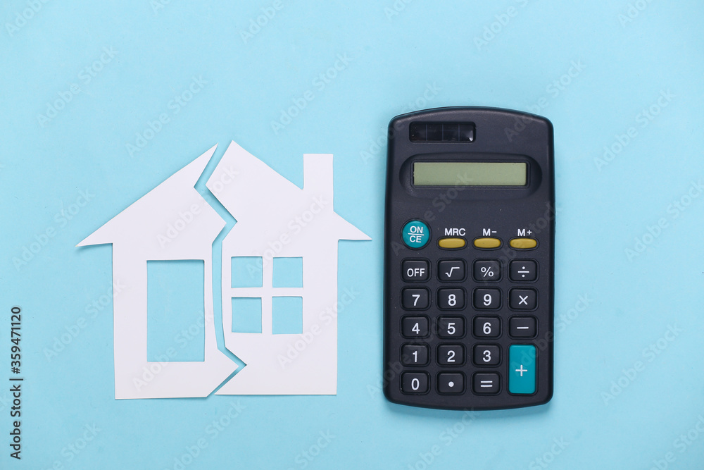 Divorce, property division concept. Split paper house and calculator on blue background Divorce, property division concept. Split paper house and calculator on blue background