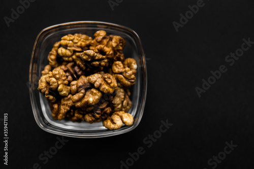 Walnut in a small plate on a black table. Walnuts is a healthy vegetarian protein nutritious food. Natural nuts snacks.