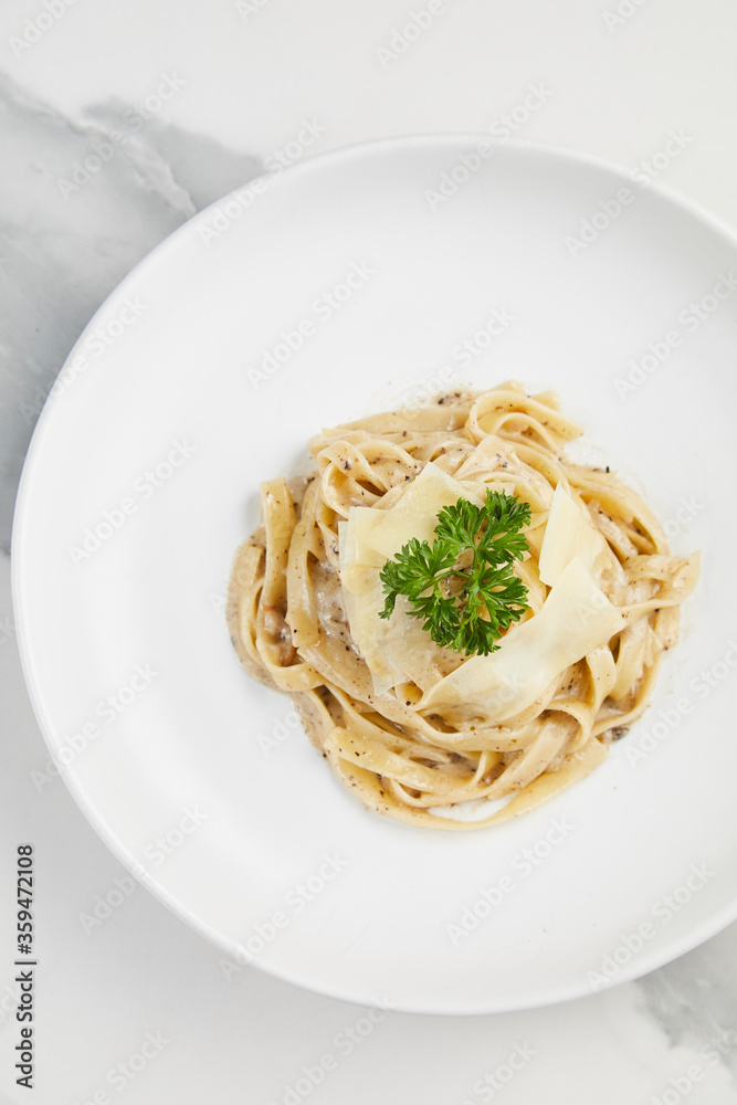 Pasta with truffle cream sauce, Tagliatelle creamy white wine sauce in white plate on white marble background
