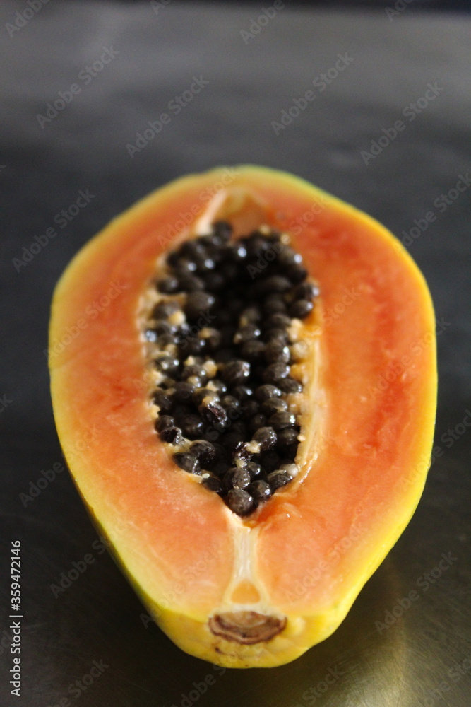 Vertical image of a cut half of a papaya fruit. Vertical image of a cut half of a papaya fruit.