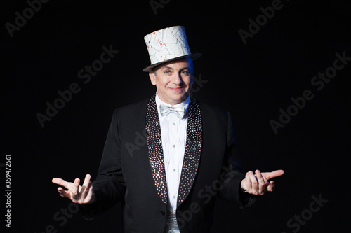 Obraz na plátně Showman performer in black suit and white silk hat on isolated black background