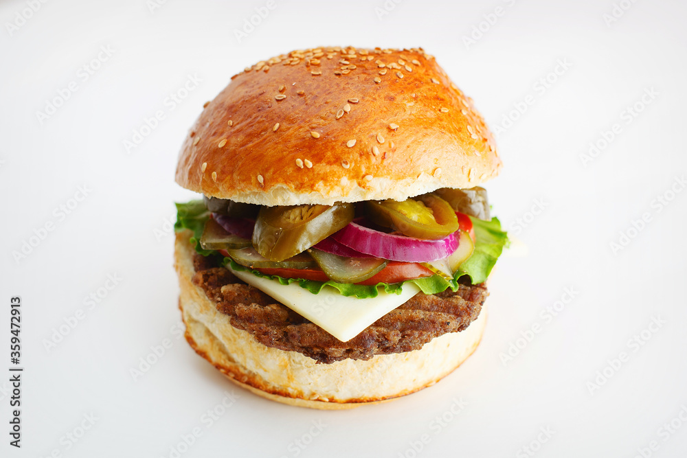 Juicy burger with onion rings, jalapeno pepper, cucumbers, lettuce, cheese on a white background