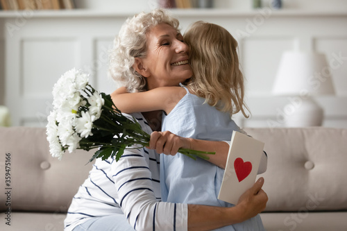 Murais de parede Sincere old grandma hugs small attentive granddaughter express her gratitude for received surprise at birthday or 8-march Woman Day