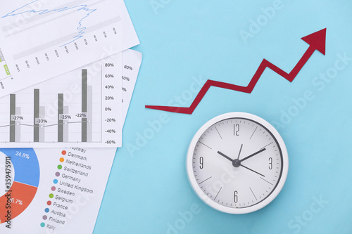 Growth upward arrow, graphs and charts, clock on blue background. Economic success. Top view