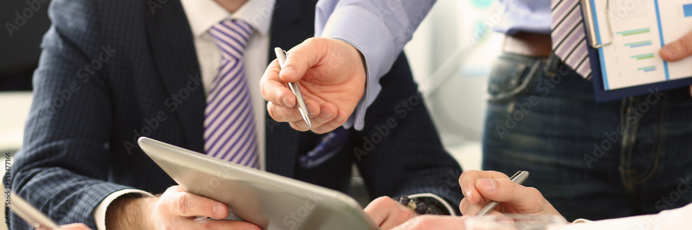 Male hand pointing in tablet pc during business meeting closeup