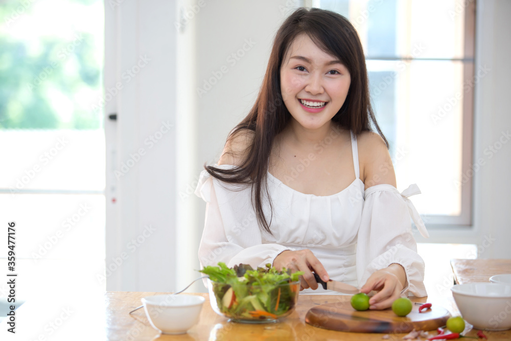 Beautiful Asian women, beautiful smile, good health, beautiful teeth, eating salad vegetable when working at home.