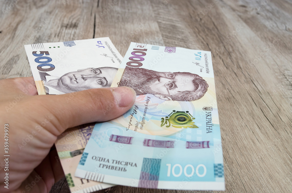 hryvnia in a female hand. Close-up. Ukrainian hryvnia. Concept of giving or taking money. hryvnia in a female hand. Close-up. Ukrainian hryvnia. Concept of giving or taking money.