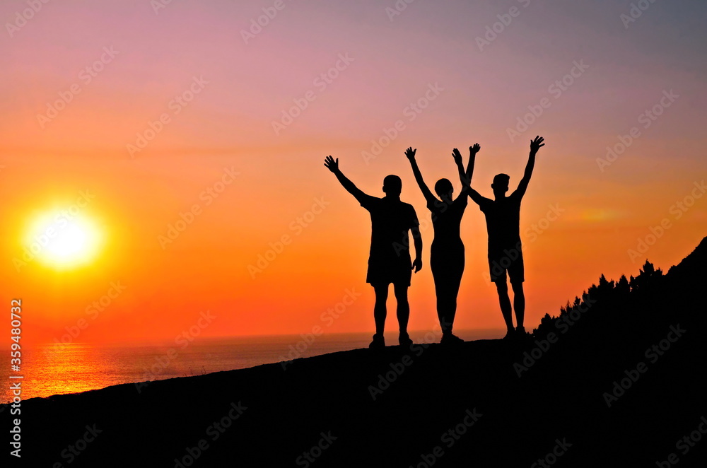 Silhouettes of happy people who admire the sea sunset.
The concept of freedom,traveling,  business success, victory and hope
