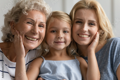 Close up concept image beautiful faces or 3 generations multi-generational relatives women portrait. Little granddaughter pose between old grandmother and young mother family smiling looking at camera
