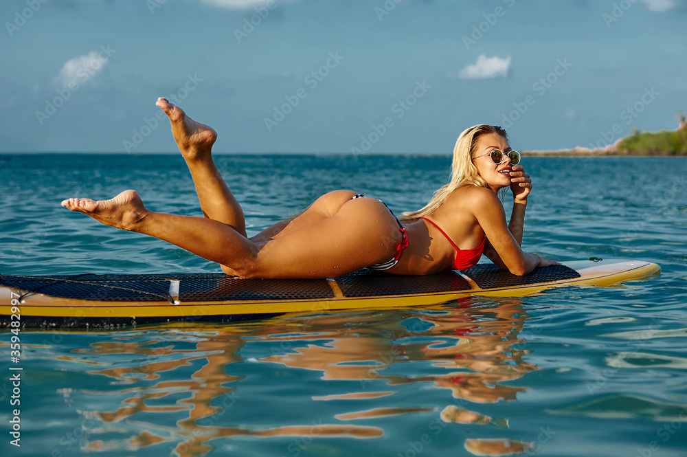 Sexy woman lying on a surfboard in the sea. Fashion portrait
