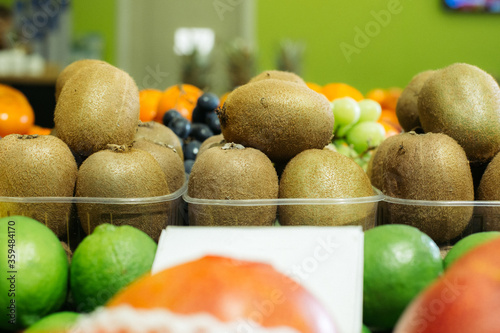 Kiwi fruits in baskets standing on supermarket shelf in grocery. Organic healthful food for sale. Vitamin eating, assortment.