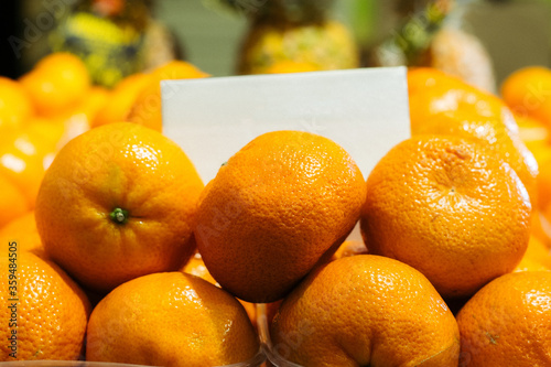 Close-up of tangerines in grocery. Orange organic tasty fruits lying on shelf in supermarket. Vitamins, dieting, vegan food, healthy eating.
