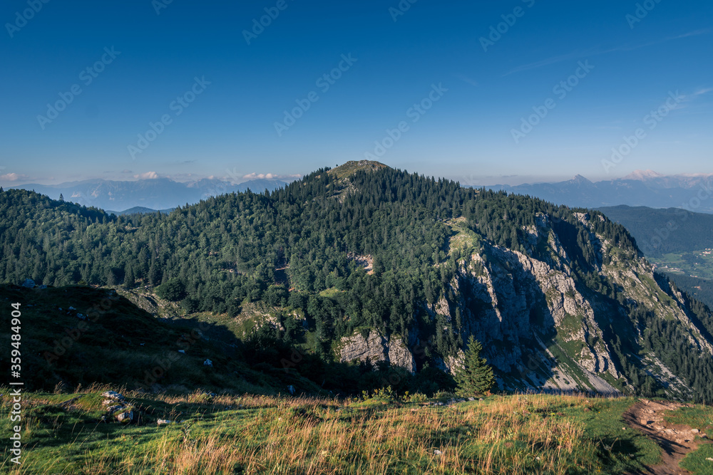 Aerial view of valley and Alps mountains, Slovenia. Hiking in summer season to the hilltop. Nature covered with green forest. Wide, elevated shot