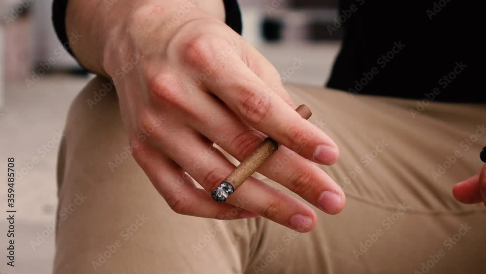cigarette in hand a man sitting on the street close up