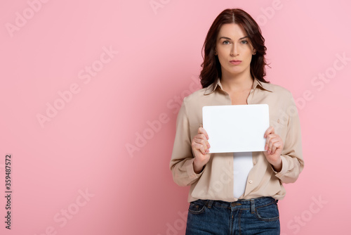 Attractive woman holding white card on pink background