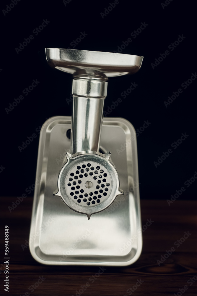 Meat grinder standing on wooden countertop on dark background Meat grinder standing on wooden countertop on dark background