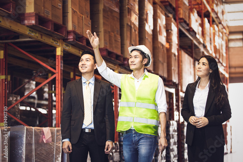 Wallpaper Mural Asian male foreman showing warehouse construction and discussing of commerce product to business man and woman or visitor at company factory