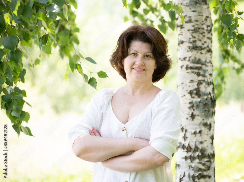 Russian woman with arms crossed near the birch in the summer Russian woman with arms crossed near the birch in the summer