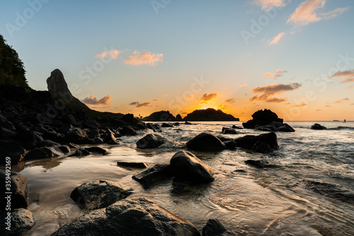Beautiful Sunset view on the rocks formation with Morro do Pico in the background at Cachorro Beach, Fernando de Noronha Marine National Park , a Unesco World Heritage site, Pernambuco, Brazil