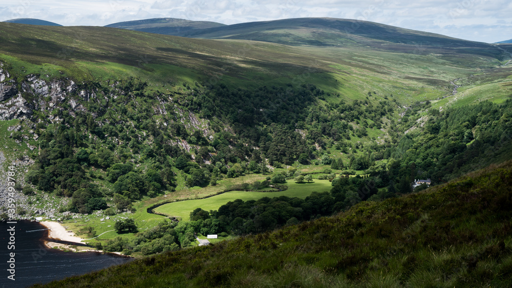 Wicklow Mountains Road. This place is famous for uncontaminated nature, misty landscapes and lakes. Typical Irish farms in background. Panoramic view during summer time Wicklow Mountains Road. This place is famous for uncontaminated nature, misty landscapes and lakes. Typical Irish farms in background. Panoramic view during summer time