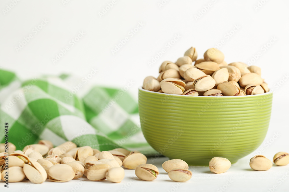 Pistachios in bowl on white wooden table Pistachios in bowl on white wooden table