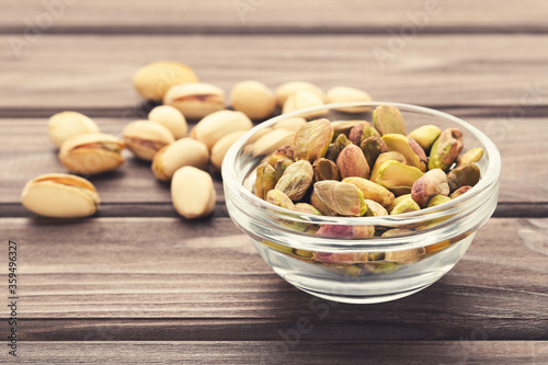 Tasty pistachios in glass bowl on wooden table