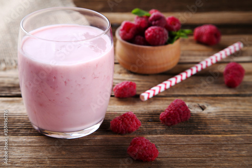 Raspberry smoothie in glass on brown wooden table