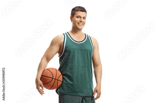 Basketball player in a jersey holding a ball and smiling at the camera