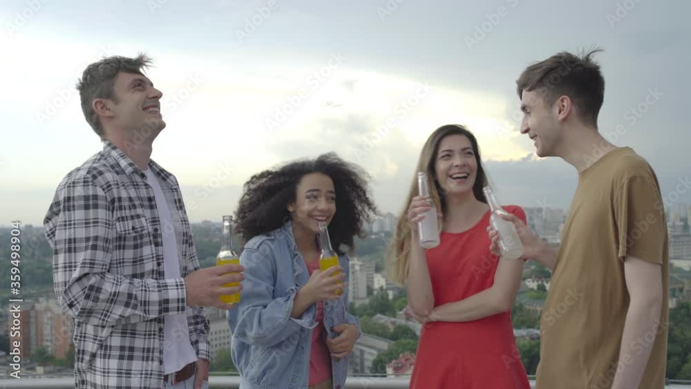 Happy young people having fun, clinking bottles at outdoor party, togetherness Happy young people having fun, clinking bottles at outdoor party, togetherness
