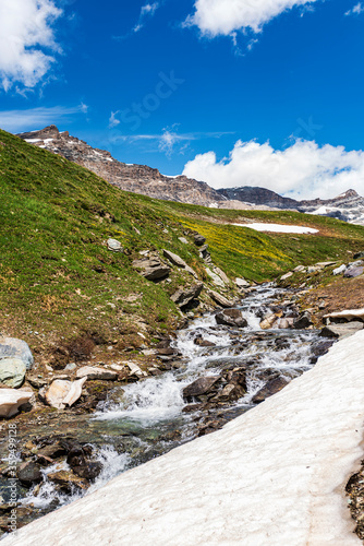 Summer landscape in italian  mountains. Meadow, nature, little waterfall and a beautiful cloudy blue sky.