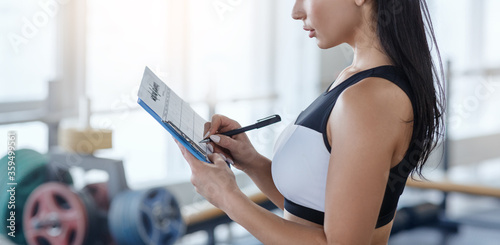Foto Personal trainer filling out workout planner at sports club, copy space