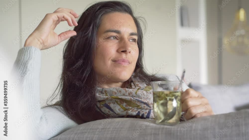 Dark-haired woman relaxing in sofa and drinking hot tea Dark-haired woman relaxing in sofa and drinking hot tea