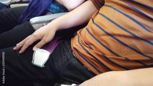 Close up of man passenger hands fasten seat belt while siting on airplane during travel trip. Fasten seat belt for safety travel.