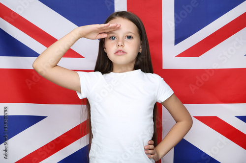 Young beautiful girl salutes on british flag background