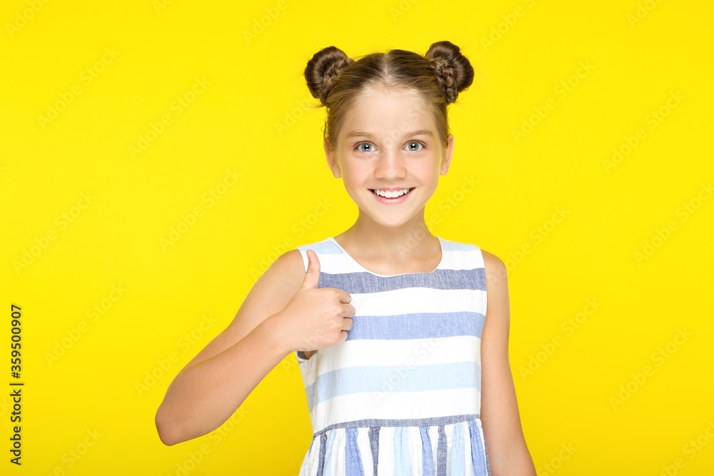 Young beautiful girl showing thumb up on yellow background Young beautiful girl showing thumb up on yellow background