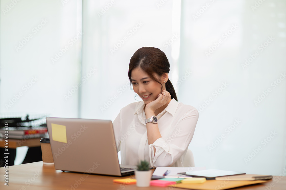 Happy Asian business woman working with laptop and smile