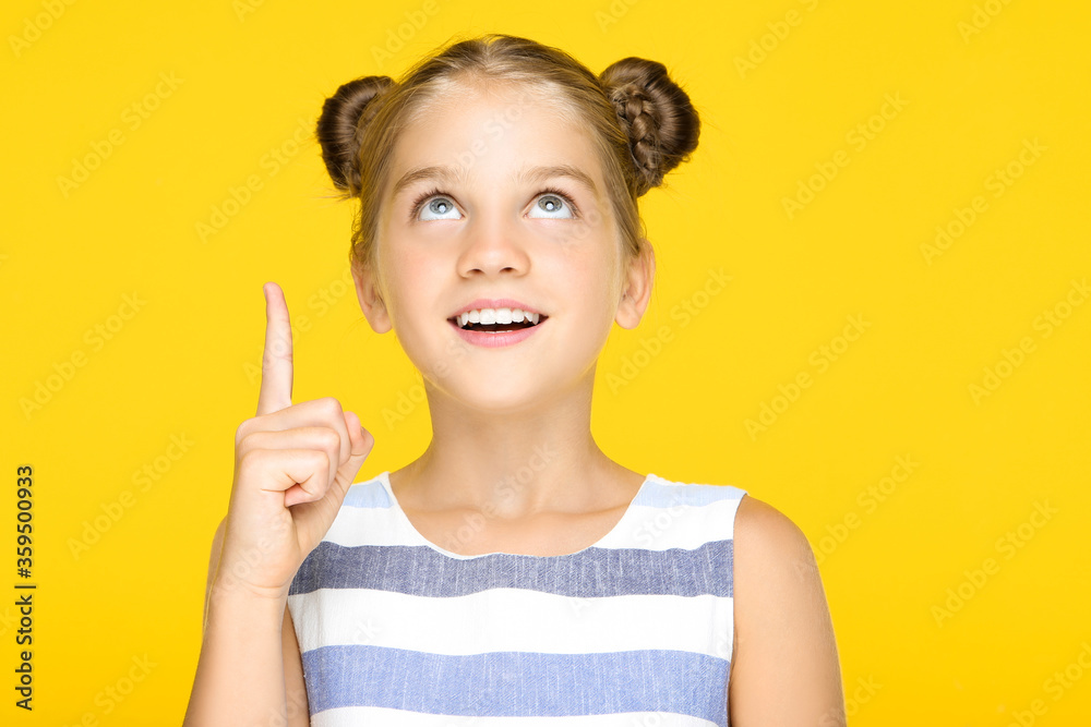 Young beautiful girl pointing by finger on yellow background Young beautiful girl pointing by finger on yellow background
