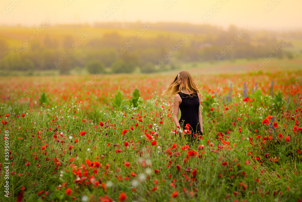 Beautiful smiling woman in red poppy field