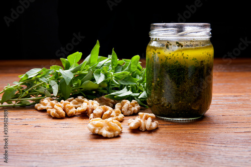 Nutrition concept - Healthy sauce of Homemade parsley pesto sauce and ingredients in glass jars over wooden background. Healthy food, Diet, Detox, Clean Eating or Vegetarian concept