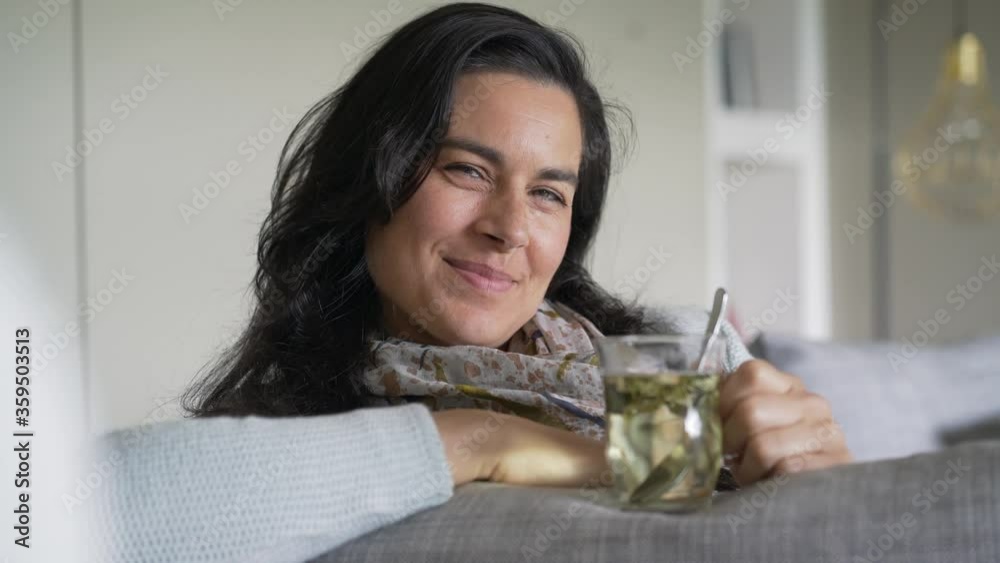 Dark-haired woman relaxing in sofa and drinking hot tea Dark-haired woman relaxing in sofa and drinking hot tea