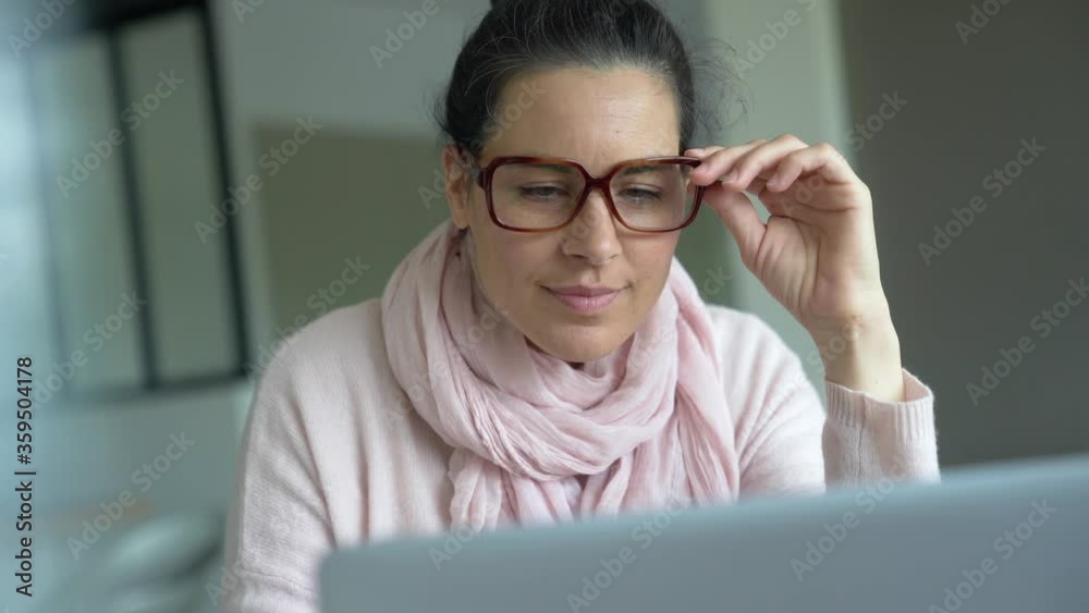 Smiling woman with dark hair drinking hot tea while connected on laptop computer Smiling woman with dark hair drinking hot tea while connected on laptop computer
