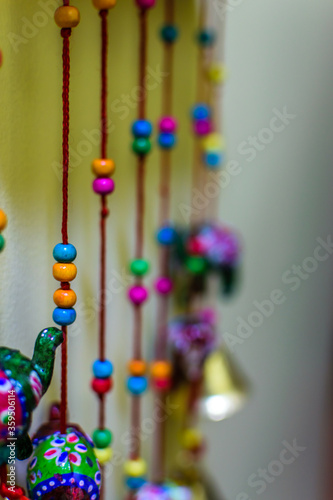 A multicolored spherical objects being hanged from red ropes . A toy for babies. Portrait view