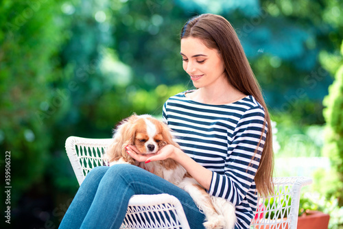 Smiling woman sitting in chair with her puppy in the garden
