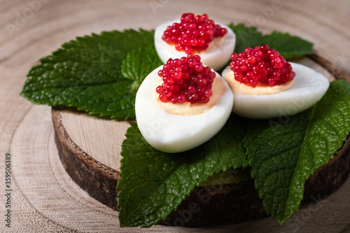 Appetizer of red caviar and small eggs on mint leaves and wooden background