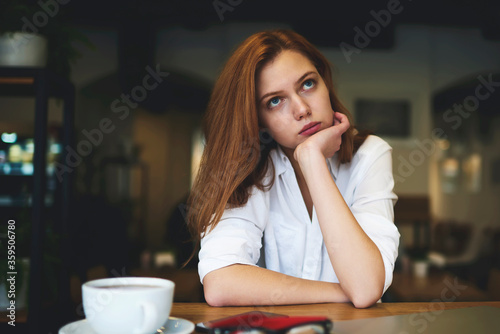 Portrait of creative female manager of design company thinking over strategy for new project feeling upset waiting for inspiration and can't find original ideas spending leisure in coffee shop